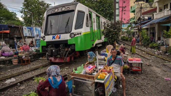 Indonesia rolls out $1.5bn stimulus as economic fears mount A train trundles past vendors selling products from makeshift stands next to the railway line in Surabaya