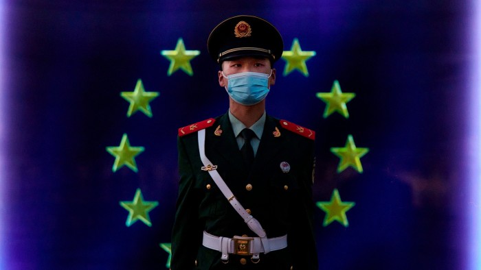 A Chinese police officer stands in front of an EU flag