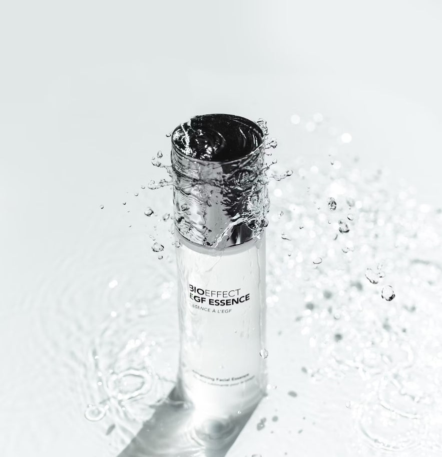 The BIOEFFECT EGF Essence bottle, featuring a chrome cap, is shown splashing in water to suggest deep hydration.