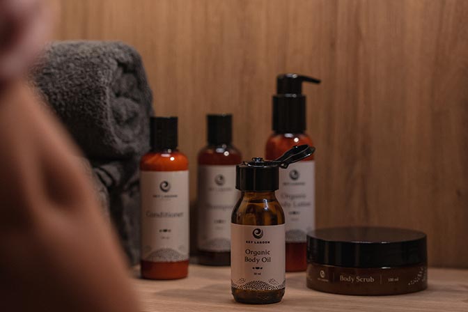 Sky Lagoon branded conditioners, shampoos, body oils, lotions, and scrubs are arranged in a spa bathroom setting.