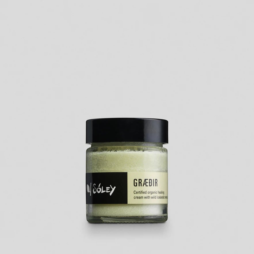Sóley Organics Graedir Certified Organic Healing Cream in a small glass jar with wild Icelandic herbs.