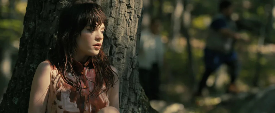 Iris (Sophie Thatcher) hides behind a tree while fleeing for her life in "Companion."