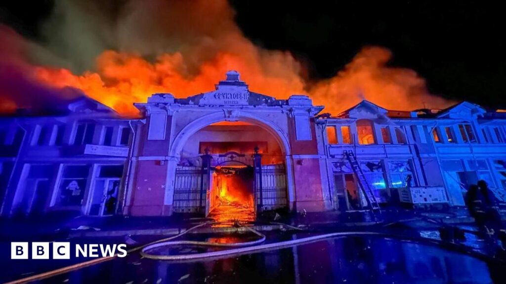 The facade of Odesa's market at nighttime, with a fire raging behind it