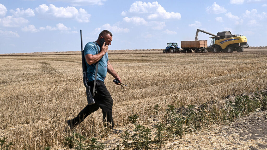A Ukranian farmer carries a gun in a field near Orikhiv, Ukraine