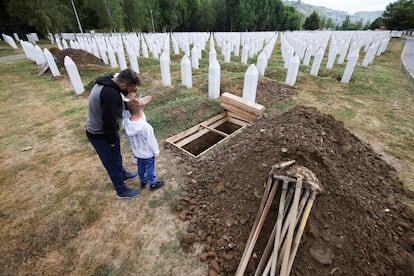 Aljo Mujcic, a Bosnian, shows his children an excavated site at the Srebrenica-Potocari Memorial Center in Bosnia and Herzegovina, Thursday.