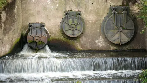Getty Images Water discharges from three cylindrical utlet pipes into the River Mersey next to the United Utilities waste water treatment plant in Stretford on June 23, 2025 in Manchester