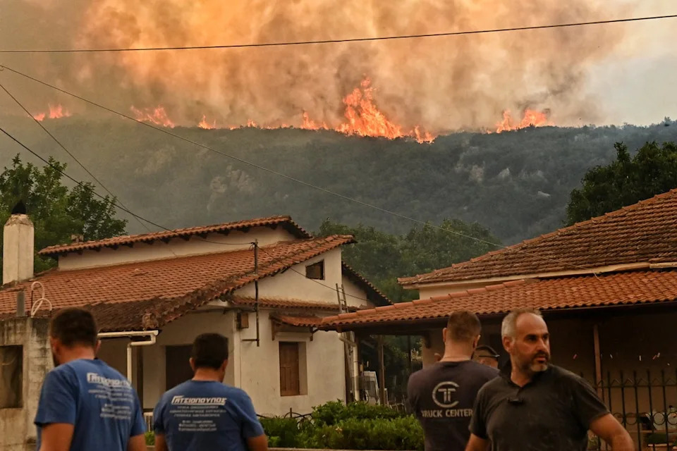 Residents watch flames rise from a wildfire burning next to the village of Karteri, in Feneos area, near Corinth, Greece, July 22, 2025. REUTERS/Vassilis Psomas (REUTERS)