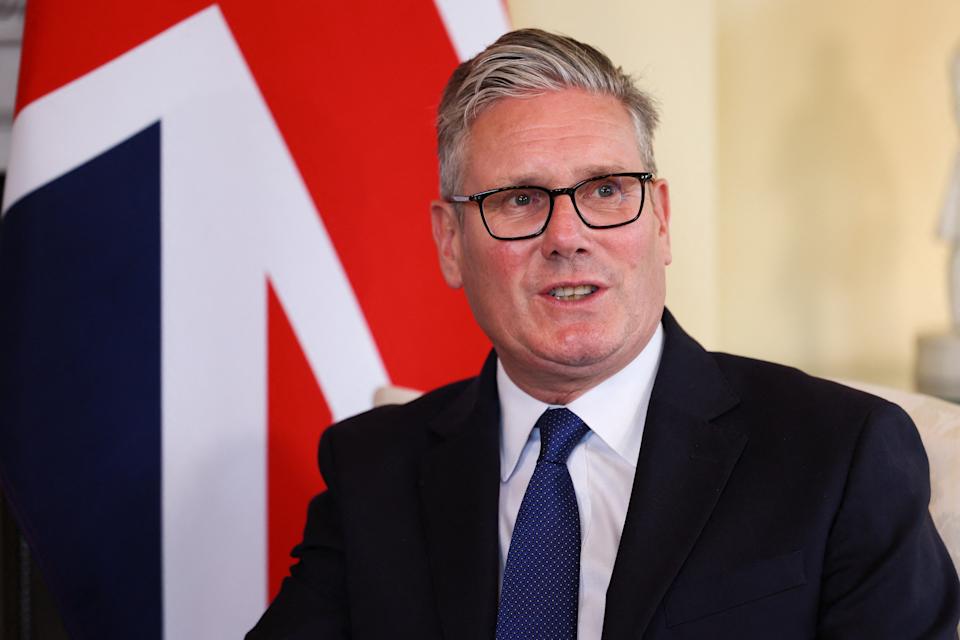 Sir Keir Starmer speaking, with a British flag behind him