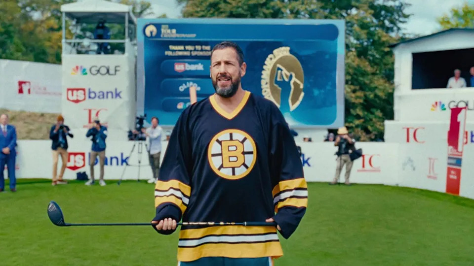  Adam Sandler as Happy Gilmore in Bruins uniform holding driver in Happy Gilmore 2. 