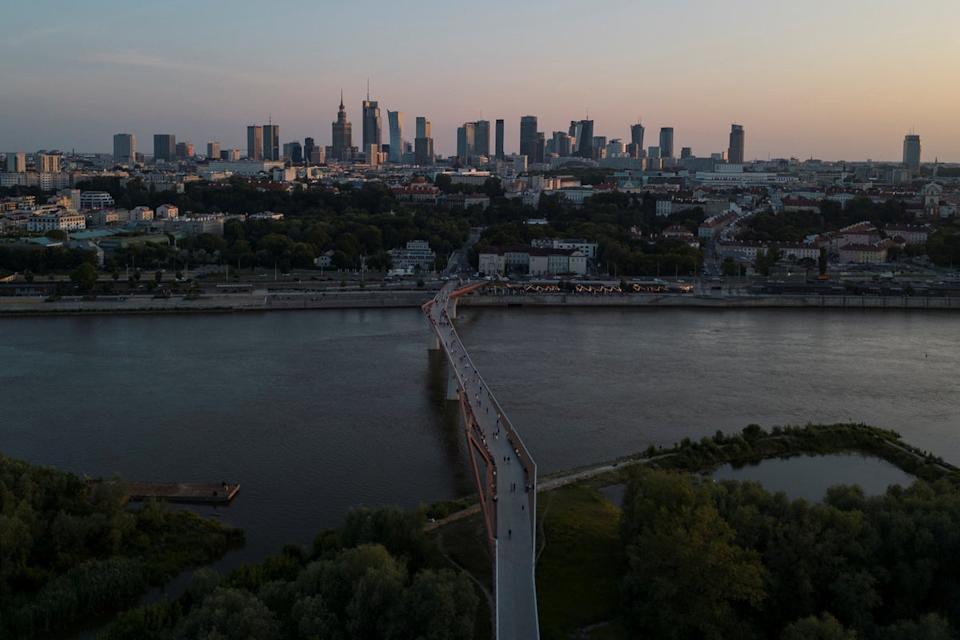A drone view shows the skyline of Warsaw with the Vistula River and a pedestrian footbridge in the foreground, and the Palace of Culture and Science visible among the city’s landmarks in the background (Reuters)