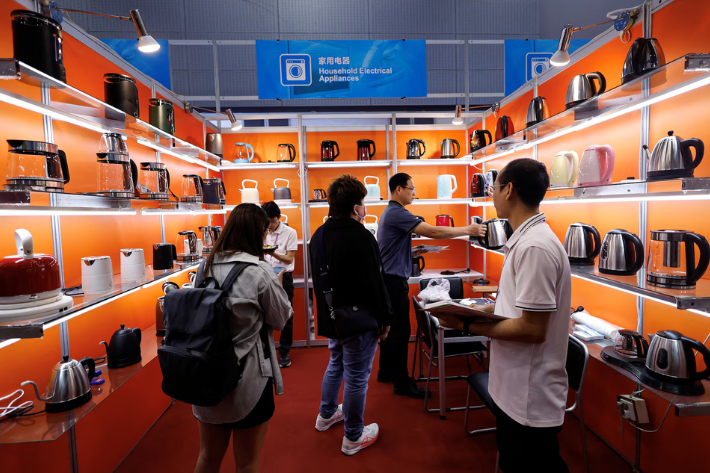 An employee attends to customers at a booth of a kettle manufacturer, at the hall of household electrical appliances during the China Import and Export Fair, commonly known as the Canton Fair, in Guangzhou, Guangdong province, China
