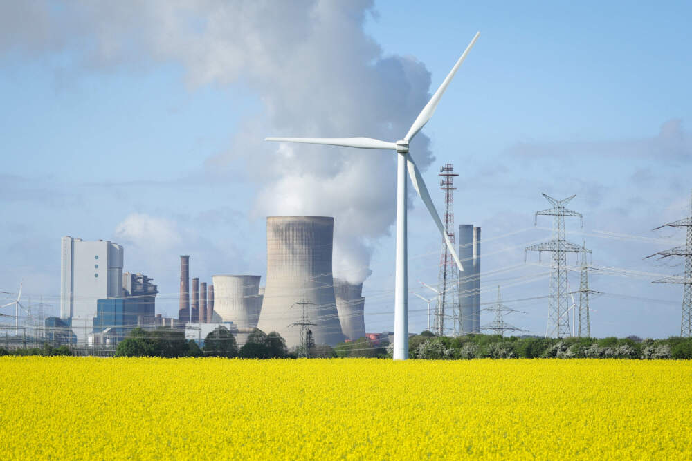Wind turbines stand next to a yellow blossoming rape field as water vapour rises from the cooling towers of a coal-fired power plant. (Andreas Rentz/Getty Images)
