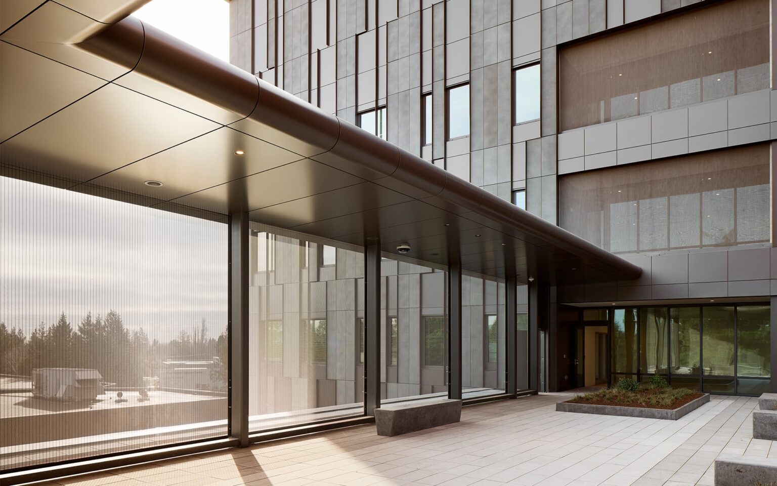 An outdoor terrace of a building with mesh like screens acting as windows  letting in natural light while also providing protection.