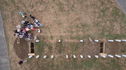 Drone view of several people near one of the graves dug for the memorial funeral, at the Srebrenica-Potocari Memorial Center in Potocari, Bosnia and Herzegovina.