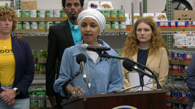 U.S. Representative Ilhan Omar talks to reporters at a podium.