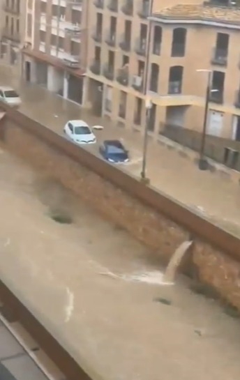 Flooded city street with cars partially submerged.