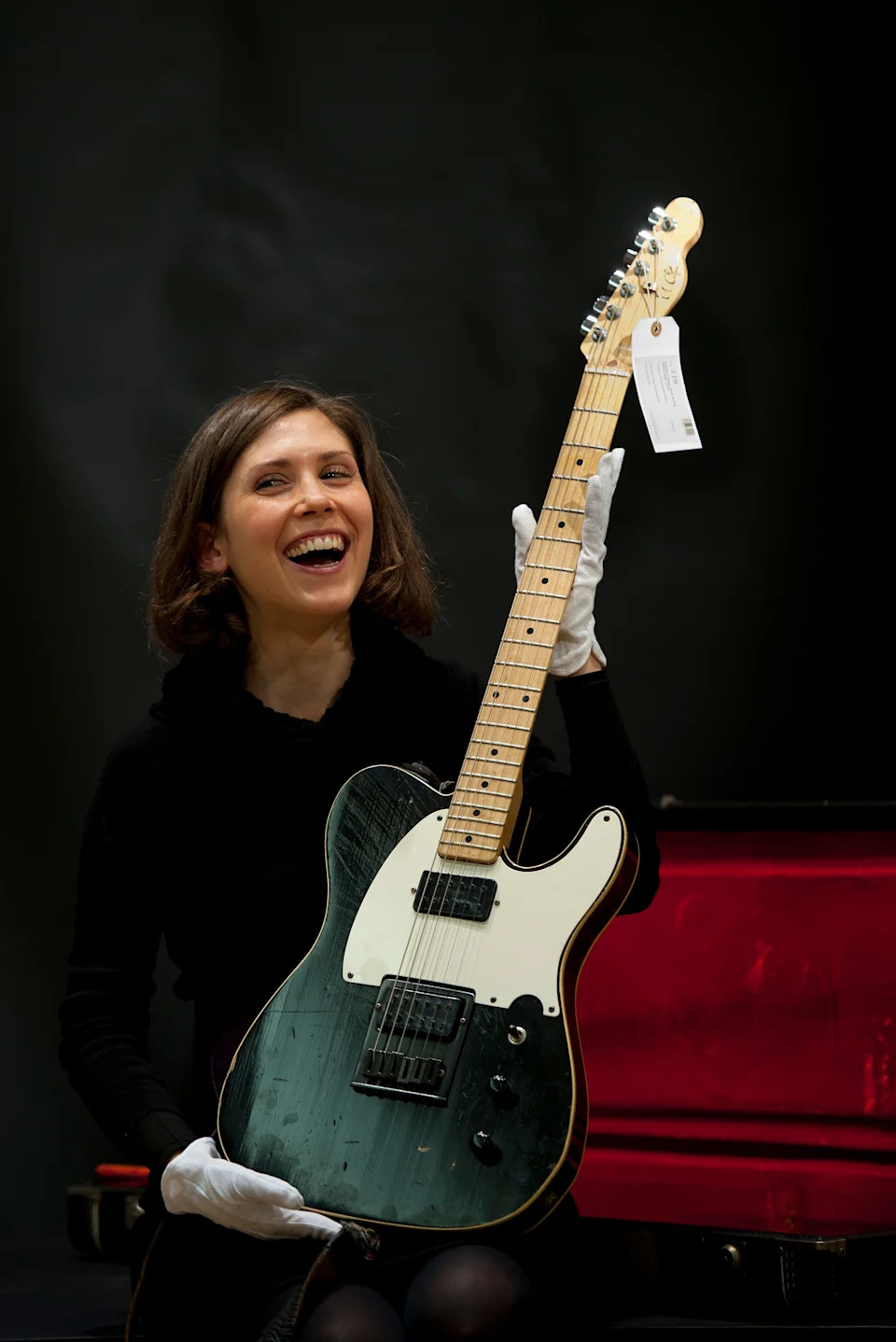 A Christies employ poses with a guitar played at Wembley in 1985 during a Live Aid performance by British rock guitarist Pete Townshend that was estimated to fetch between 10,000 and 15,000 British pounds (16000 - 24000 US dollars).