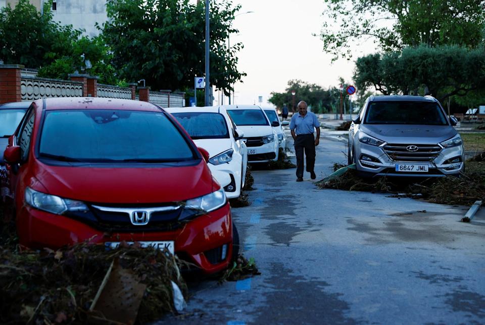 A man walks by damaged cars in Cubelles following flash flooding over the weekend (REUTERS)