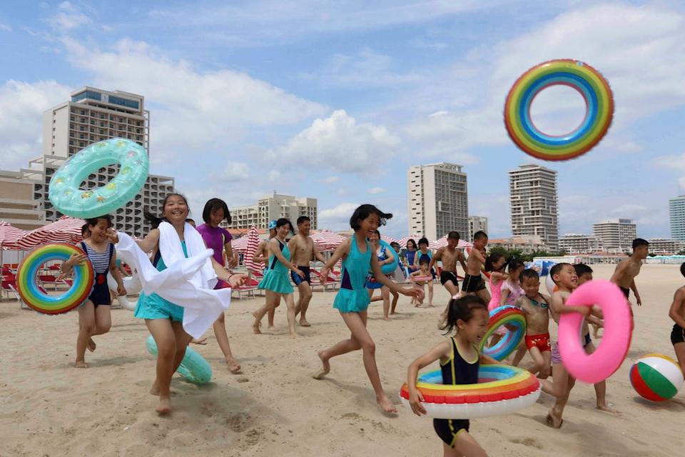 Children run into sea at the Wonsan-Kalma resort on 2 July 2025 (AP)