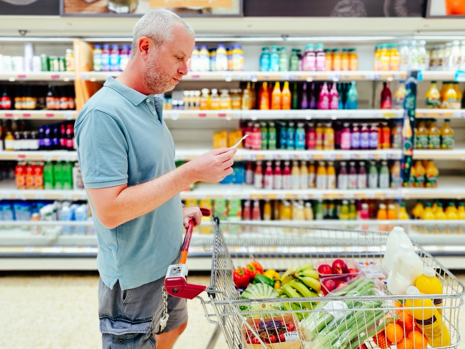 Man checking shopping list in supermarket aisle.