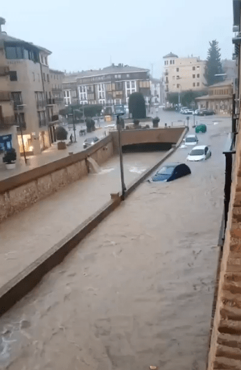 Flooded city street with several submerged cars.