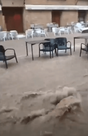 Flooded outdoor cafe with tables and chairs.