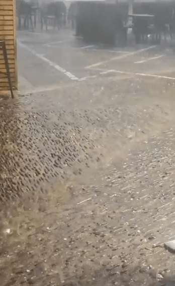 Rain heavily falling on a paved surface.