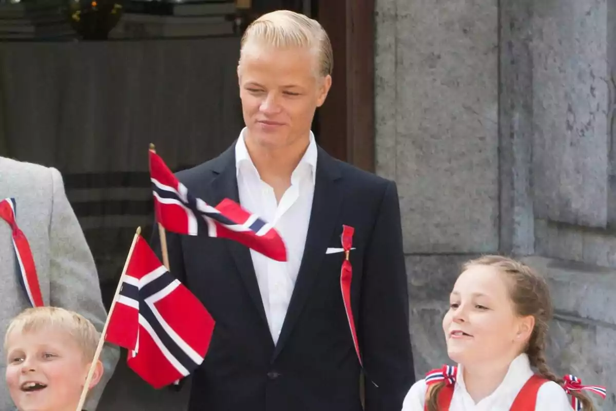 Marius Borg and two children hold Norwegian flags as they celebrate an event.