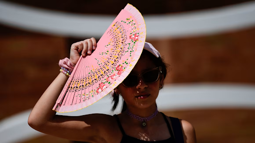 A woman protects herself from the sun with a fan during the heat in Seville, Spain, on Monday.