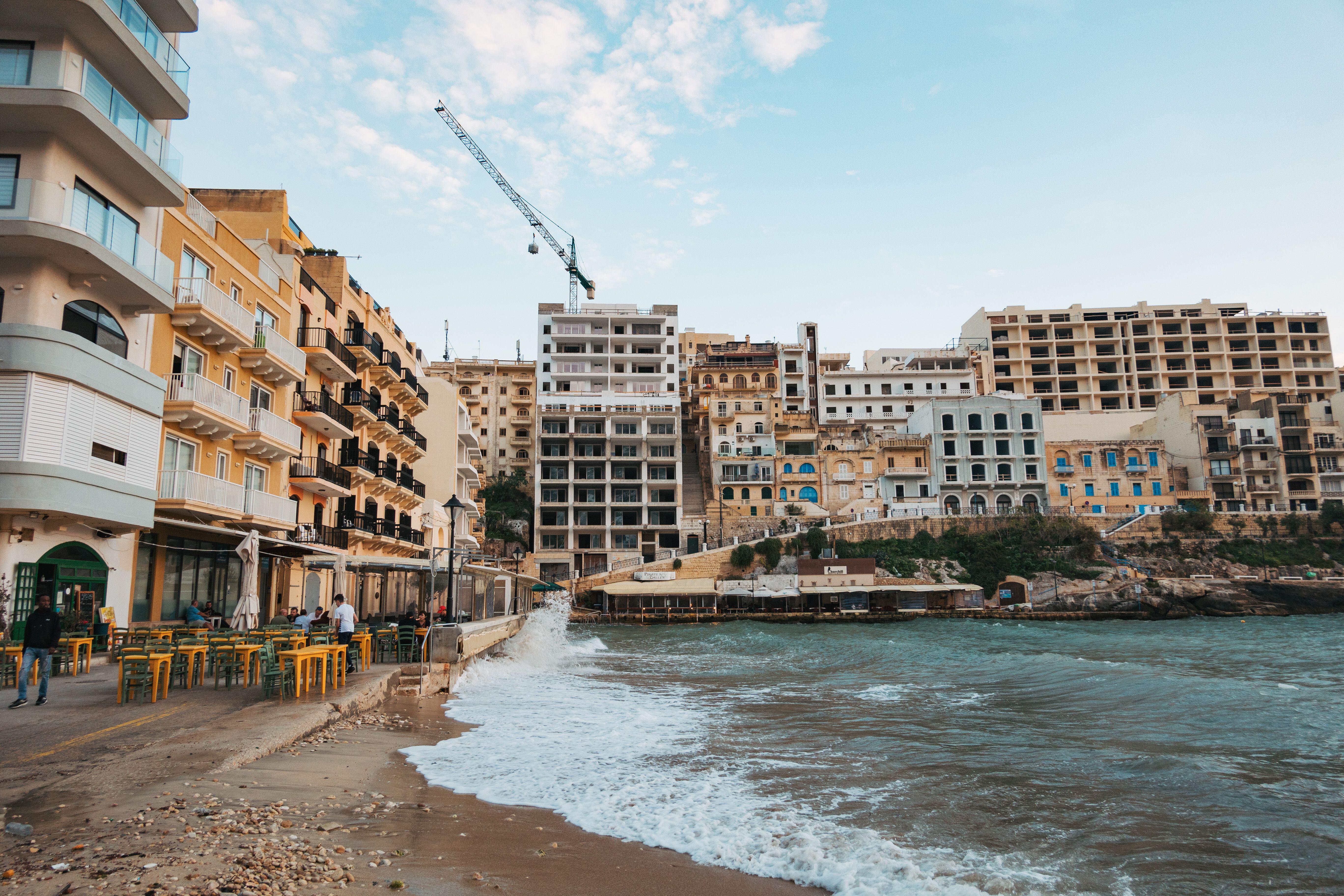 Xlendi Bay, Gozo, Malta: apartments, restaurants, and a construction crane overlooking the sea.