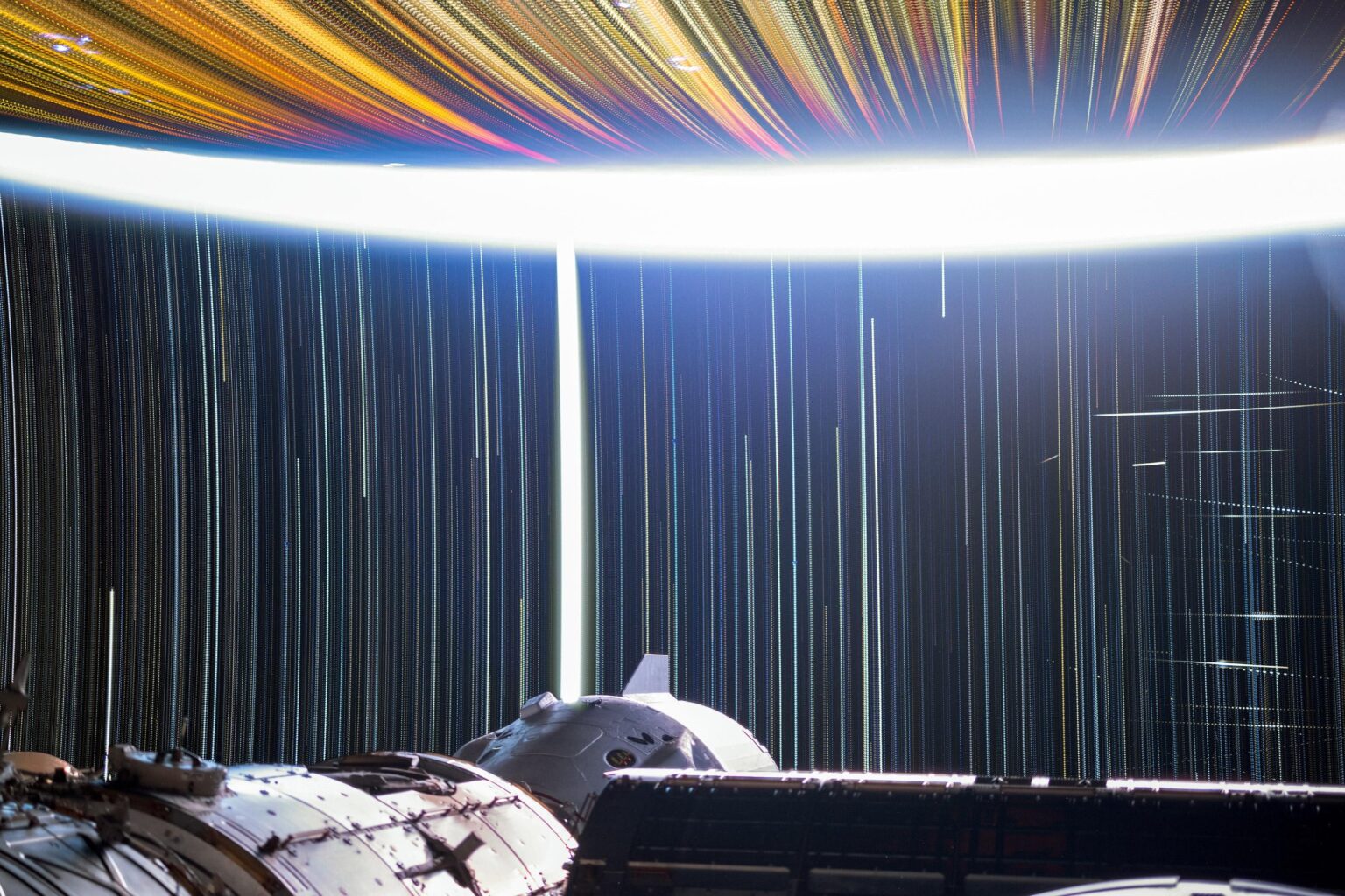 Star trail time exposure from the ISS, with Moon, satellites, cities, and stars.
