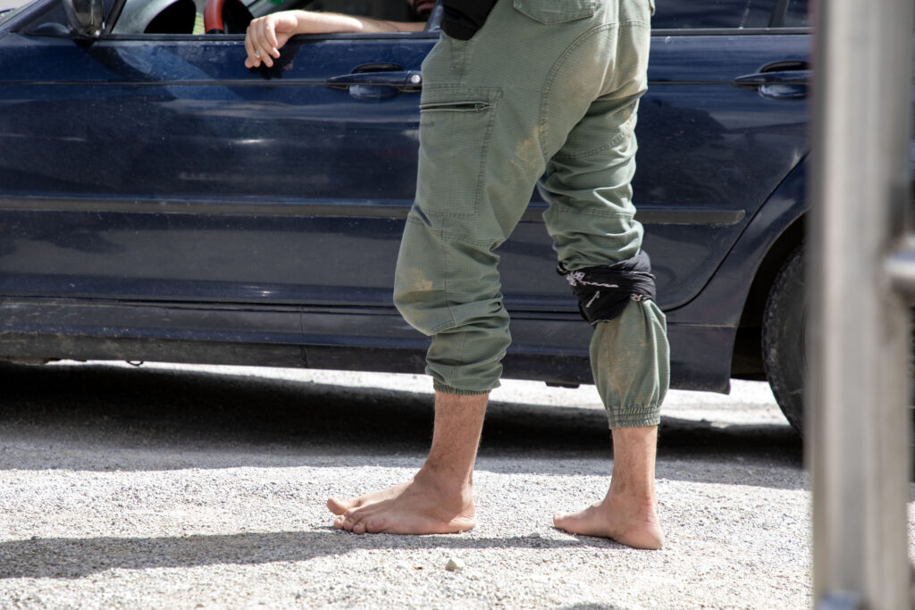 A migrant wounded after attempting to cross the Croatian border negotiates with a taxi driver for a ride back to Lipa (Maryam Ashrafi)