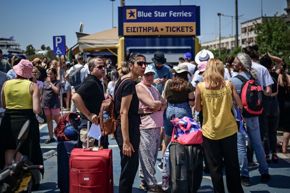 Crowds of people with luggage wait in line at a ferry ticket office.