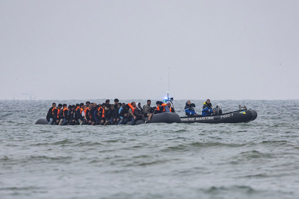 Migrants in a boat being followed by a French Maritime Gendarmerie boat in the English Channel.