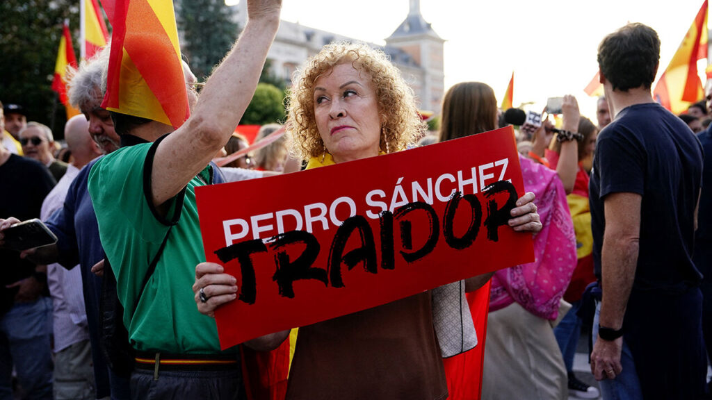 A woman holds a placard that reads "Pedro Sanchez Traitor" at a protest in Madrid, Spain