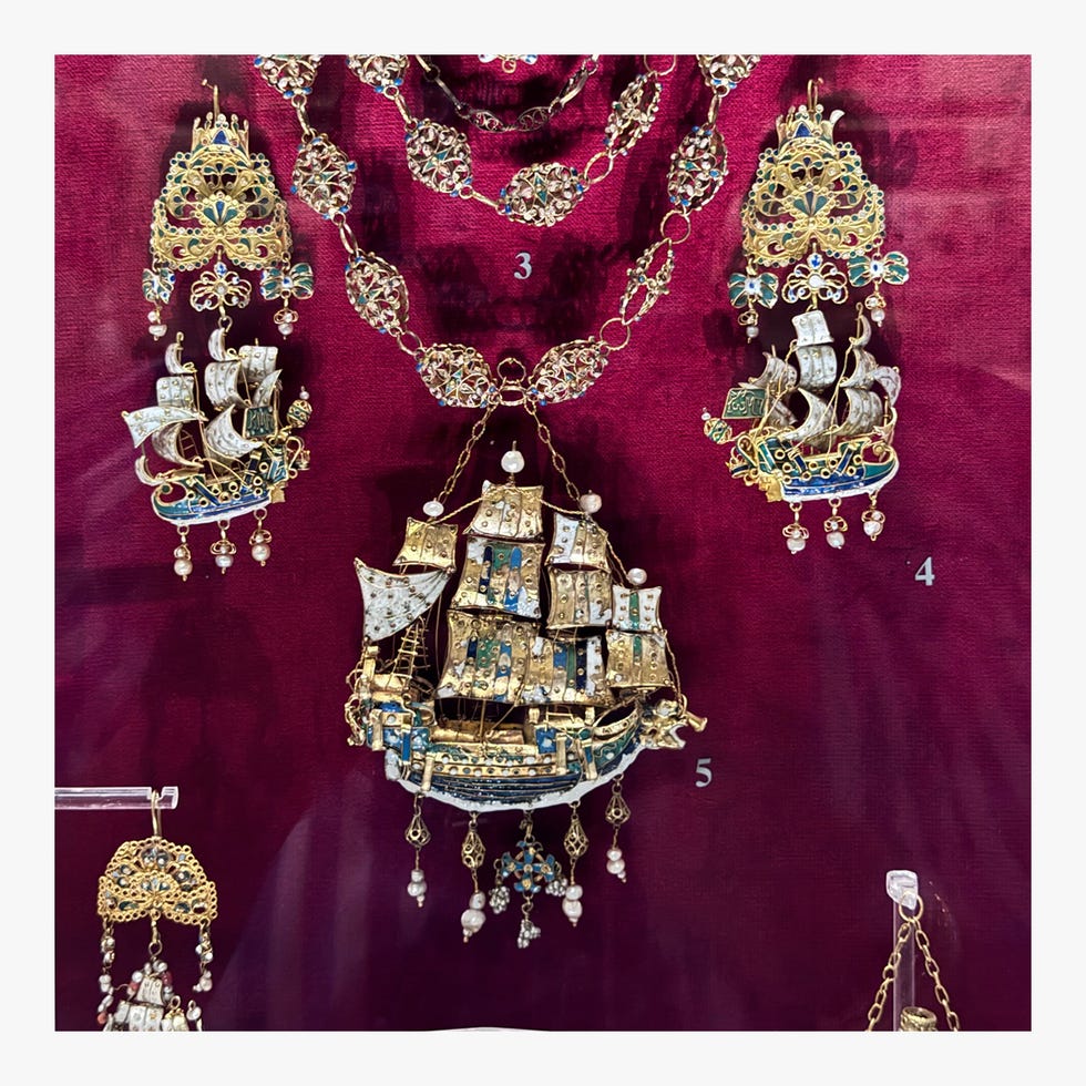 Decorative maritime-themed jewelry displayed against a rich maroon background.
