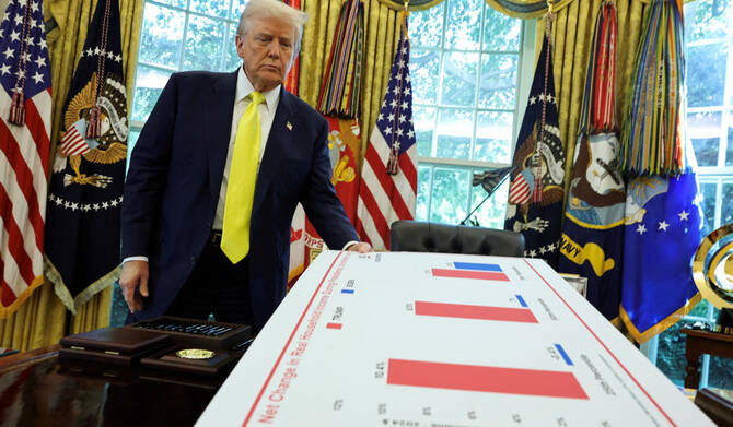 President Trump holds a board, as he makes an announcement on the economy, in Washington. (REUTERS)