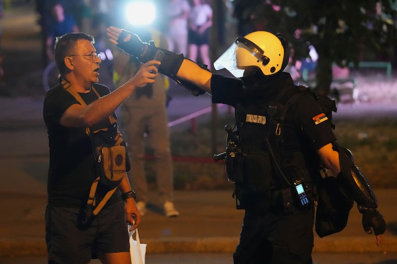 A Serbian riot police officer directs a man filming after clearing people blocking a street in Belgrade (Darko Vojinovic/AP)