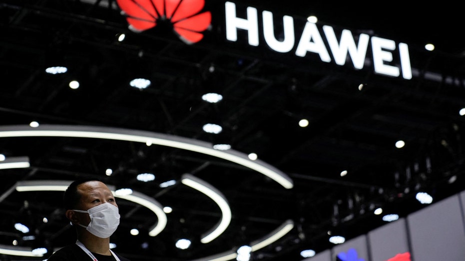 FILE PHOTO - A person stands by a sign of Huawei during World Artificial Intelligence Conference, following the coronavirus disease (COVID-19) outbreak, in Shanghai, China, September 1, 2022.