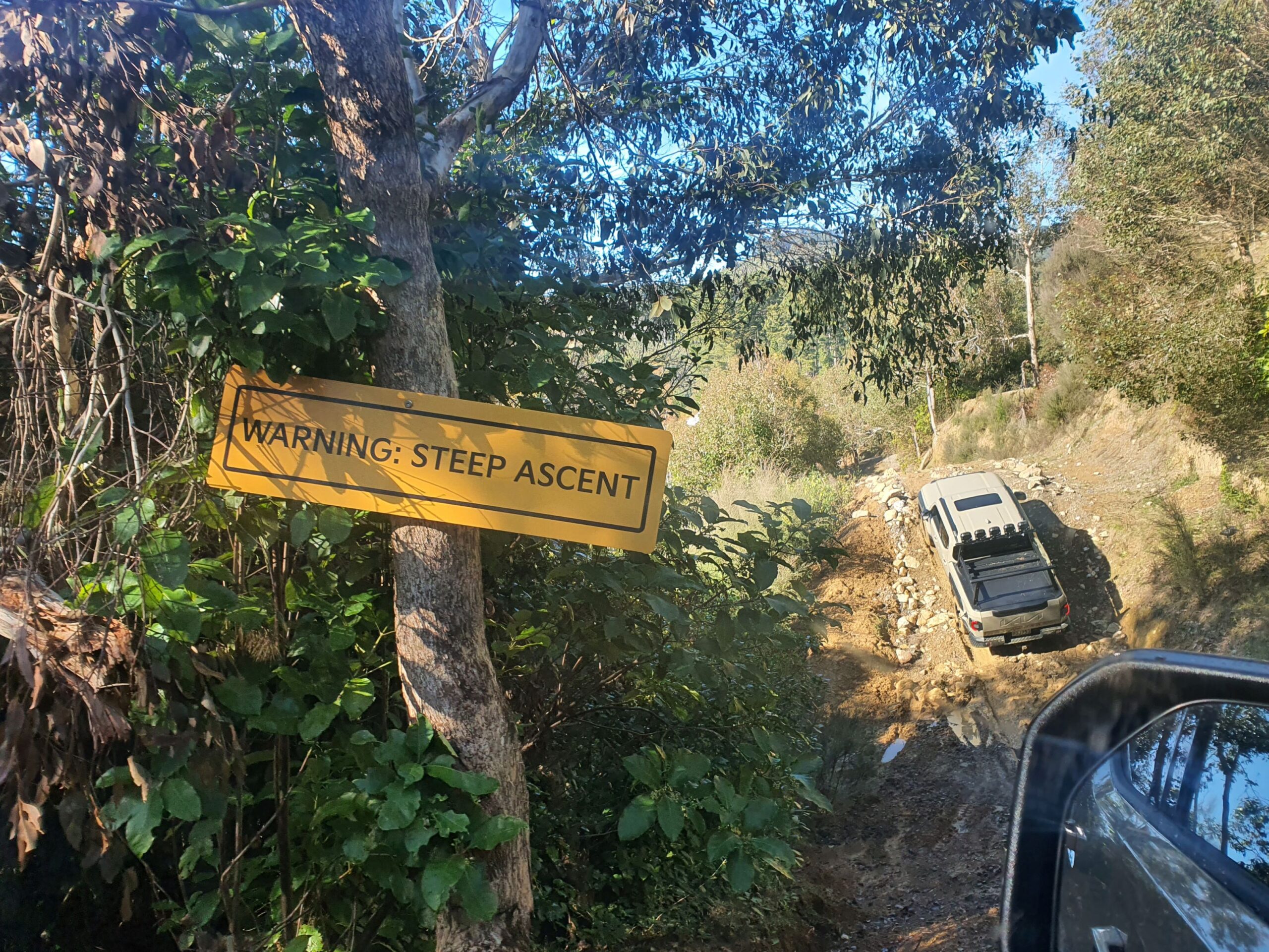 A photo of a Kia Tasman climbing a steep dirt covered incline on the 2025 Kia Tasman launch at Dirt Farm, Te Horo, Hautere, just outside of Wellington.