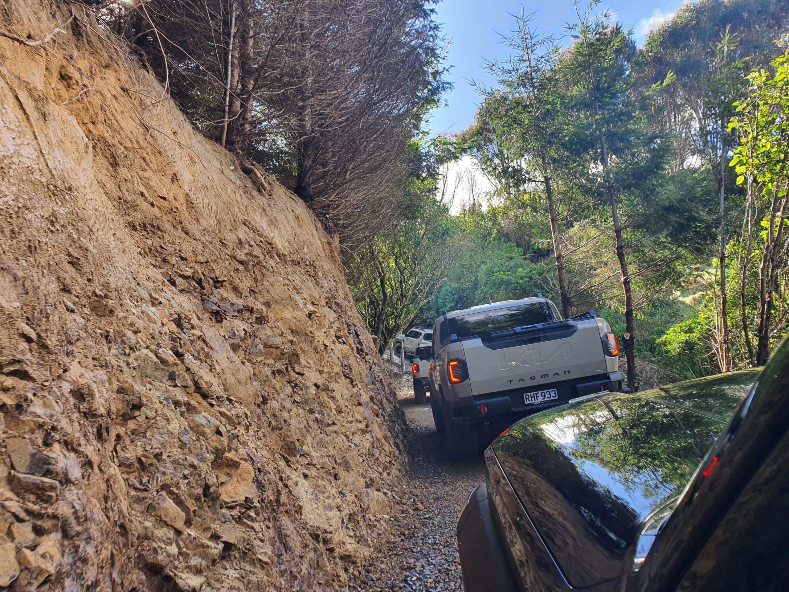A photo of a convoy of Kia Tasman utes tackling a steep hill climb on the 2025 Kia Tasman launch at Dirt Farm, Te Horo, Hautere, just outside of Wellington.