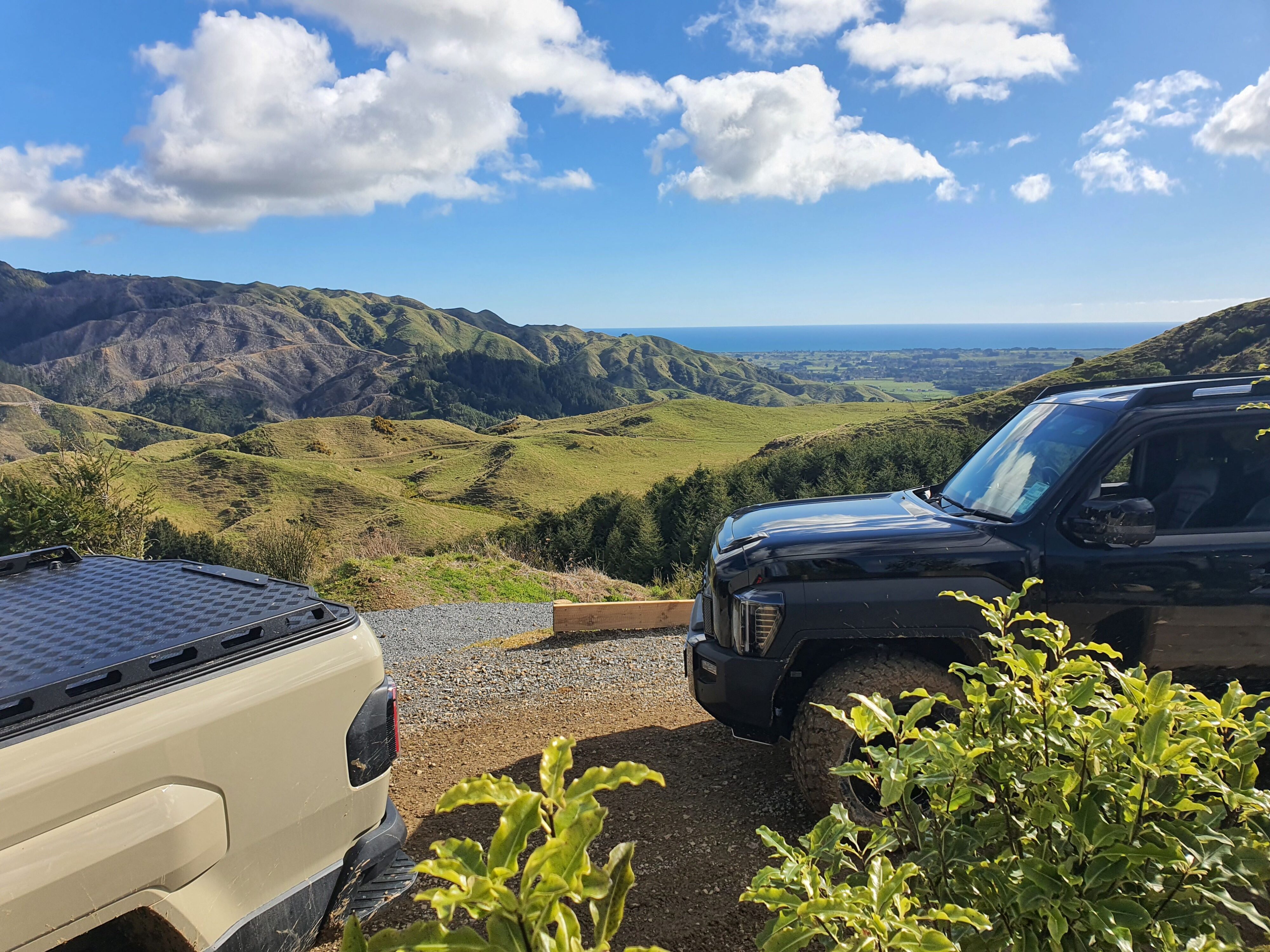 A photo of the Tasman Sea visible in the background, spotted through two Kia Tasman utes on the 2025 Kia Tasman launch at Dirt Farm, Te Horo, Hautere, just outside of Wellington.