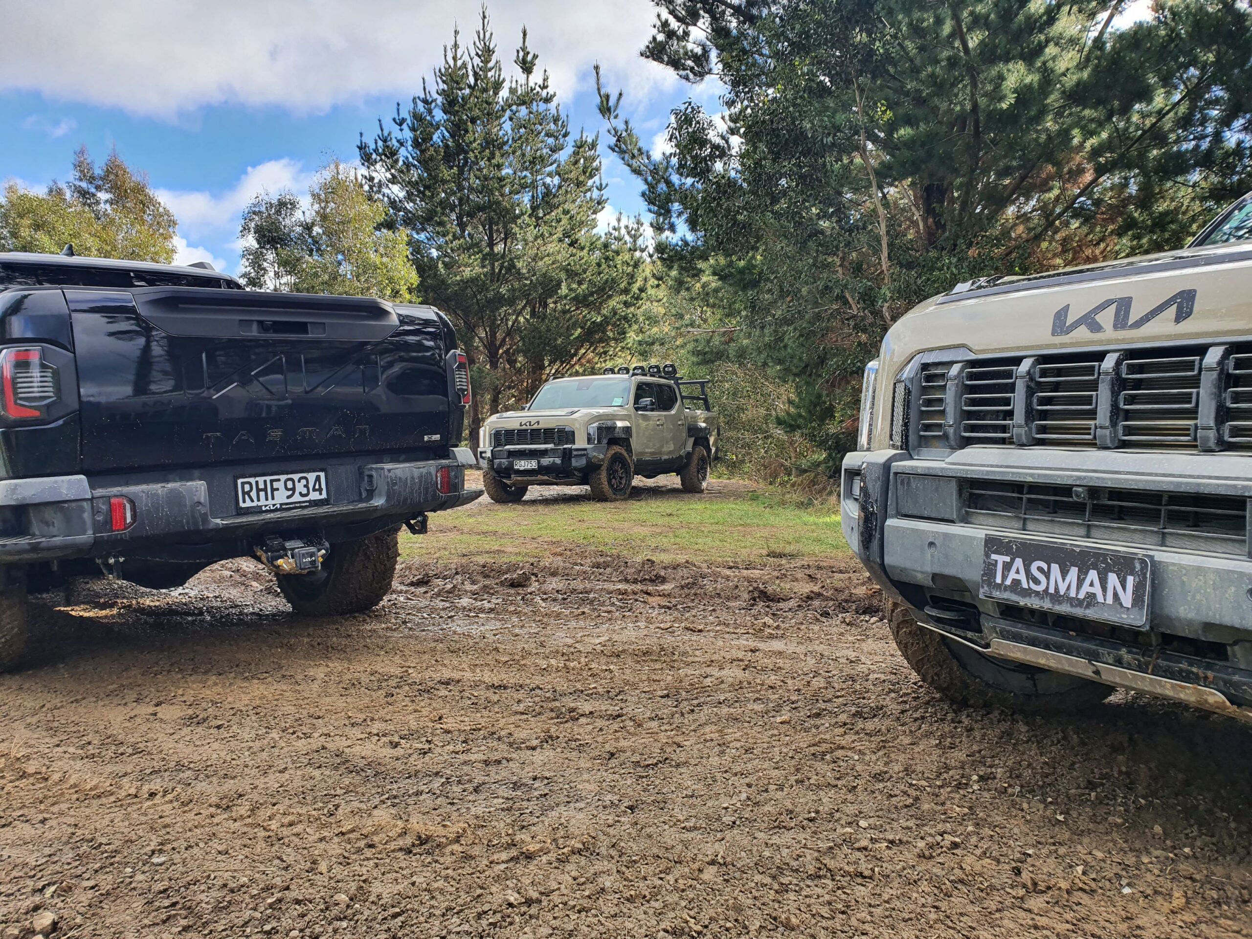 A photo of a Kia Tasman visible through two other Kia Tasman utes on the 2025 Kia Tasman launch at Dirt Farm, Te Horo, Hautere, just outside of Wellington.