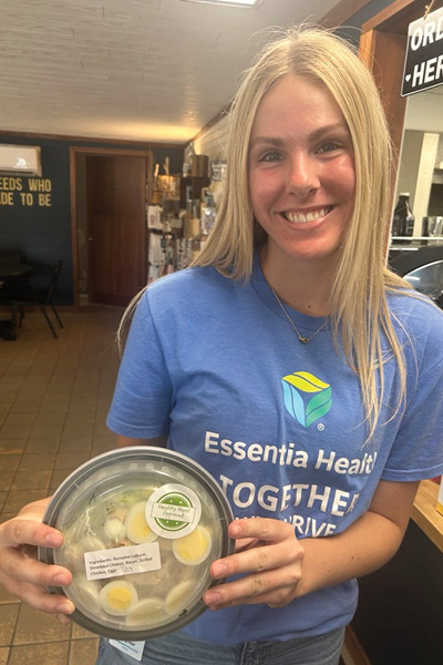 young woman with blonde hair smiling and holding a salad