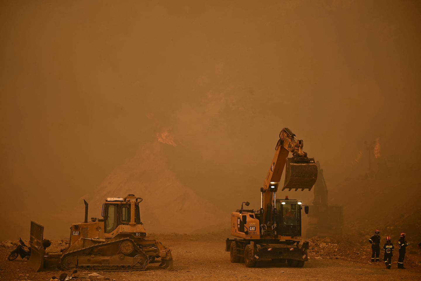 Firefighters use construction machinery during efforts to extinguish a wildfire near the city of Patras, western Greece on Wednesday.