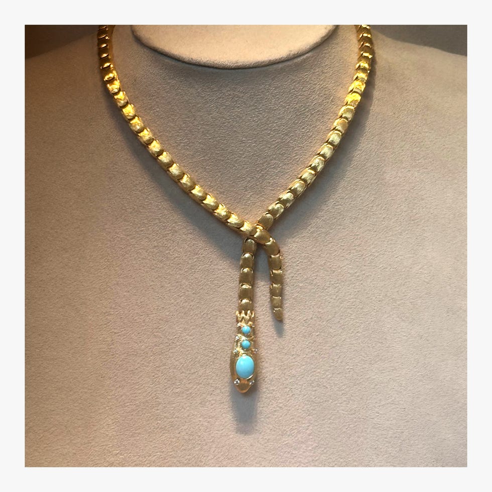 Gold necklace featuring a snake-like design with turquoise accents.