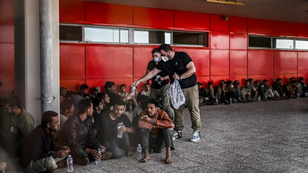 Greece Prepares for Stricter Border Policies ━ The European Conservative Migrants receive food and bottles of water as they are gathered by Greek coast guard officers after disembarking from a cargo ship, in the port of Lavrio, south of Athens, on July 10, 2025.