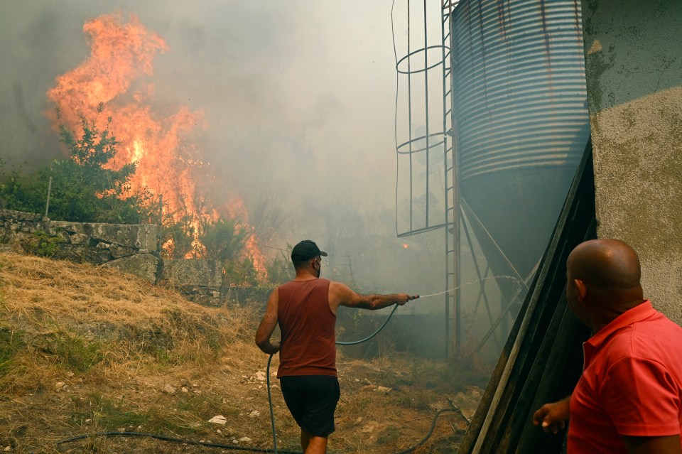 People fighting a wildfire near buildings in Vilarino, Spain.