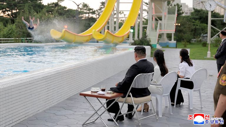 Kim Jong Un and his daughter Kim Ju Ae watch a person on a waterslide.
Pic: KCNA/Reuters