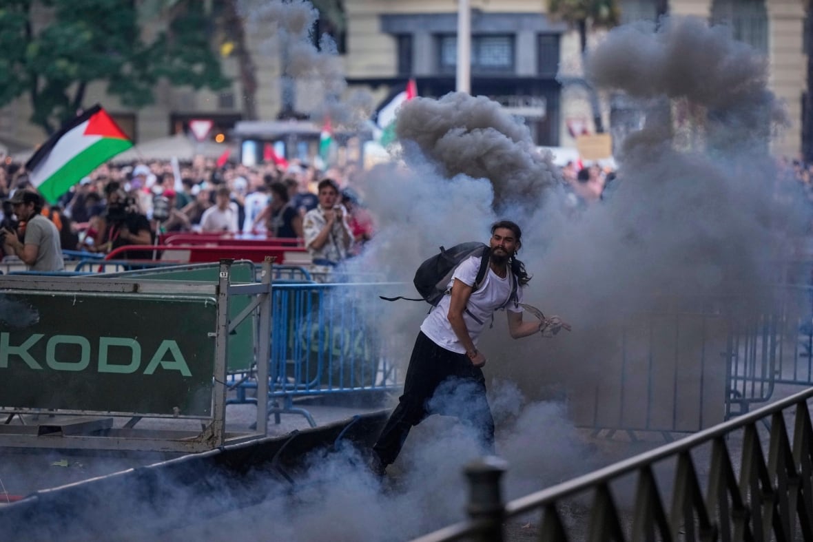 A protester throws a teargas cannister.